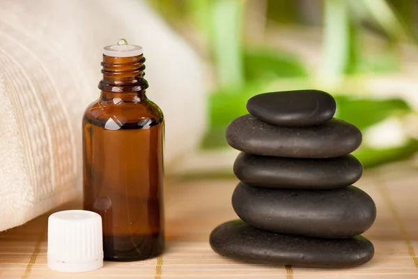 Masaje rocas y botella de aceite de aromaterapia —  Fotos de Stock