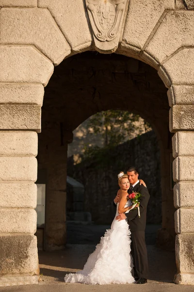 Portrait of bride and groom under stone arch — Stock Photo, Image