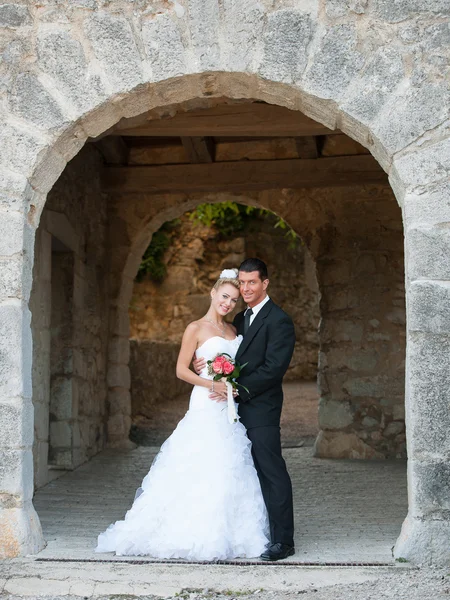 Portret van de bruid en bruidegom onder stenen boog — Stockfoto