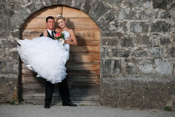 Жених держит невесту перед деревянной дверью — стоковое фото