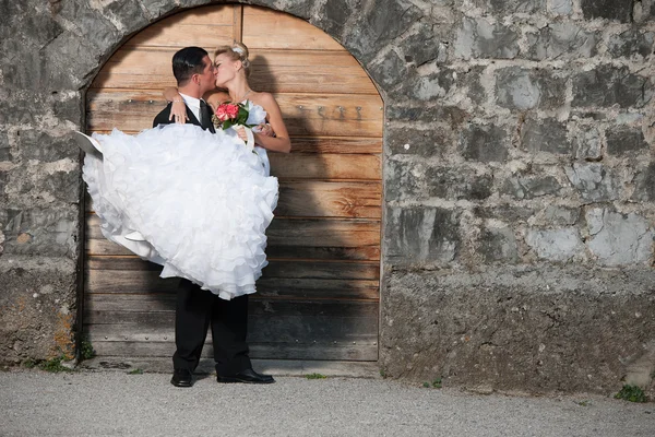 Жених держит невесту перед деревянной дверью — стоковое фото