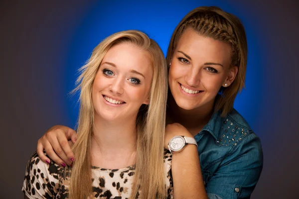 Deux belles filles souriant sur fond bleu studio — Photo