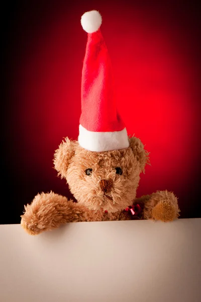 Urso de pelúcia com cartão de texto branco no fundo de Natal vermelho — Fotografia de Stock