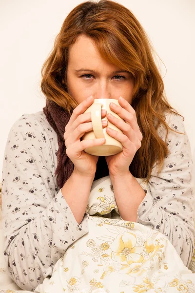 Mulher doente com feaver beber xícara de chá quente sob cobertor — Fotografia de Stock