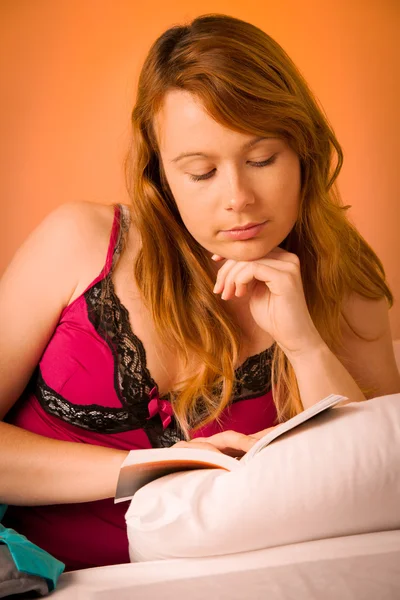 Beautiful young woman reading book in bed — Stock Photo, Image