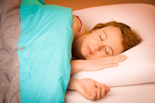 Женщина на подушке в постели, покрытая одеялом — стоковое фото