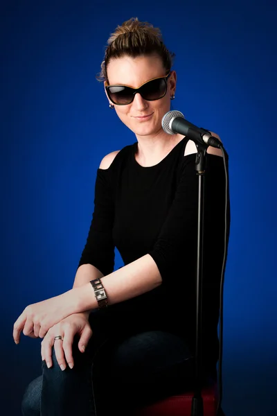 Woman singer on bluue background with microphone — Stock Photo, Image