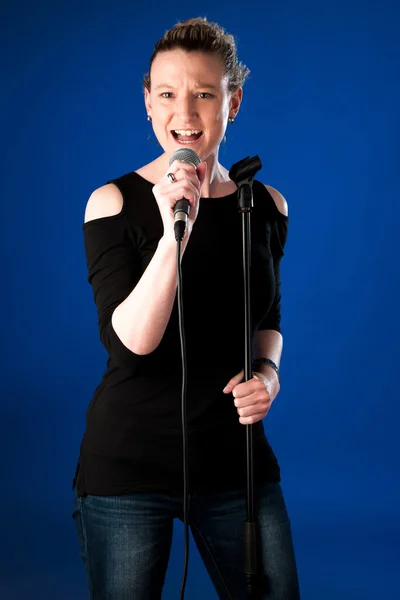 Woman singer on bluue background with microphone — Stock Photo, Image