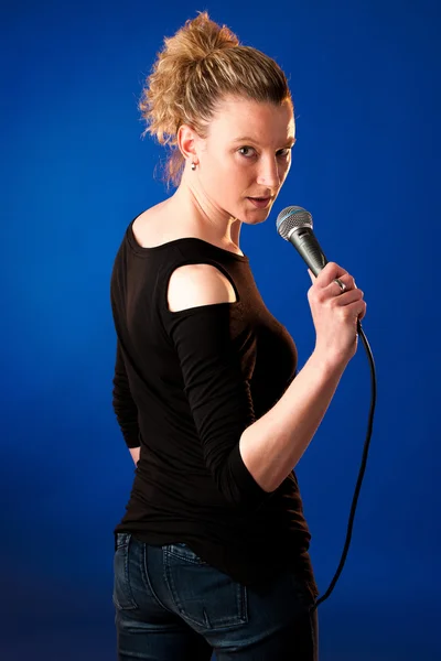 Женщина-певица на фоне синего с микрофоном — стоковое фото