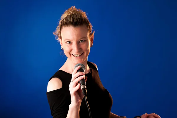 Mujer cantante sobre fondo azul con micrófono —  Fotos de Stock