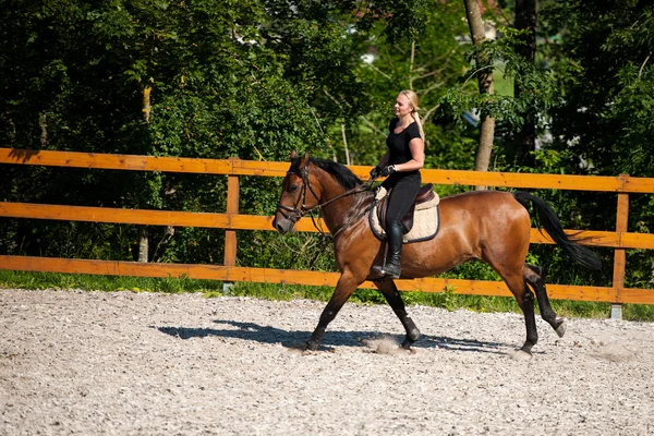Hermosa joven rubia montando un caballo — Foto de Stock