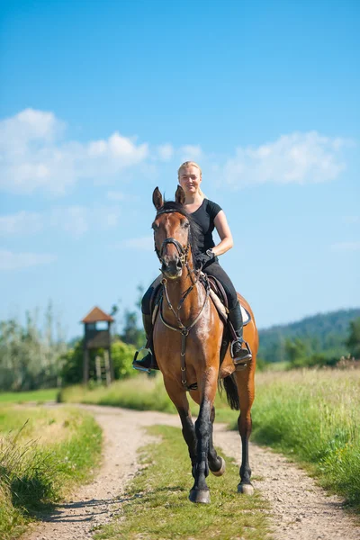 Beautiful young blonde woman riding a horse — Stock Photo, Image