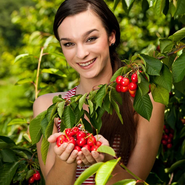 Güzel bir genç kadın kiraz plantasyonda yiyor. — Stok fotoğraf