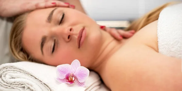 Young woman lying on massage table receiving face massage. Beauty treatment concept.