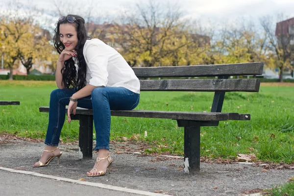 Νεαρή γυναίκα που κάθεται στον πάγκο — Φωτογραφία Αρχείου