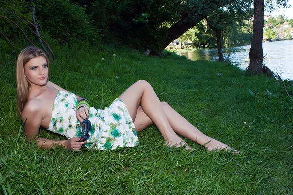 Belle jeune femme assise au bord de la rivière — Photo