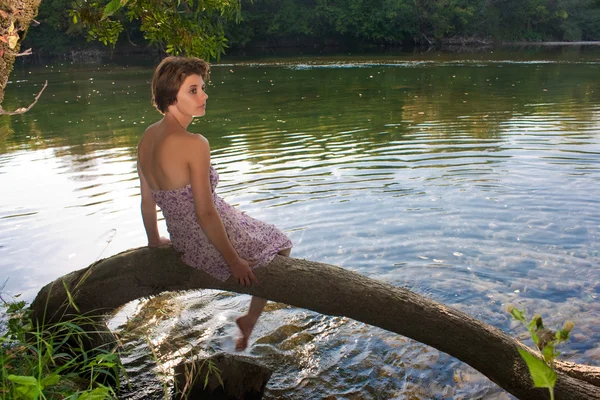 美しい若い女性は川のそばに座って — ストック写真