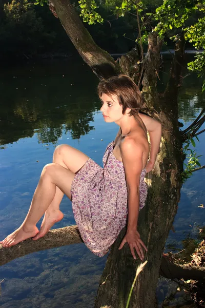 Beautiful young woman sitting by the river — Stock Photo, Image