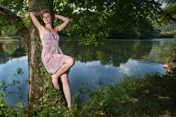 Beautiful young woman standing by the river — Stock Photo, Image