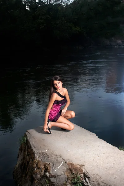 Beautiful young woman standing by the river — Stock Photo, Image