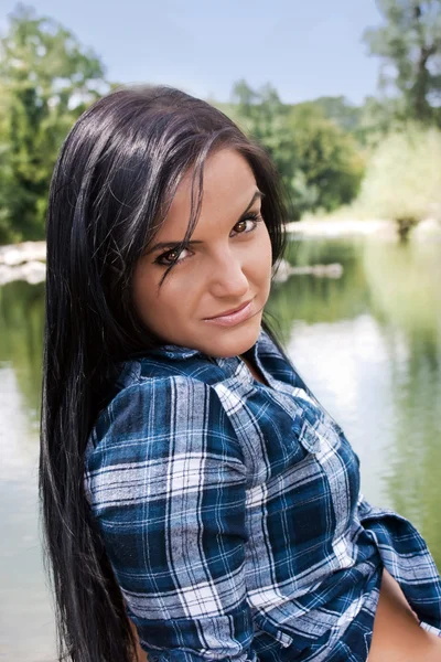 Belle jeune femme assise au bord de la rivière — Photo