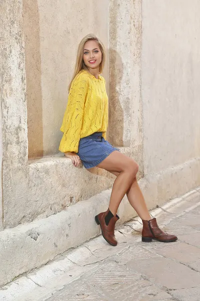 Piękna Blondynka Pozuje Ścianie Żółtym Swetrze Dżinsowej Spódnicy — Zdjęcie stockowe