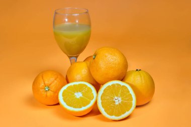 Portakal arkaplanda bir bardak sıkılmış meyve suyu ile tam ve dilimlenmiş portakal. 