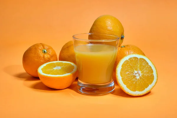 Ολόκληρα Και Κομμένα Φέτες Πορτοκάλια Ένα Ποτήρι Χυμό Πορτοκαλί Φόντο — Φωτογραφία Αρχείου