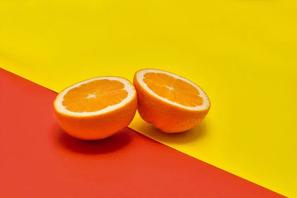 Dwie Połówki Pomarańczy Kombinacji Żółtego Czerwonego Tła — Zdjęcie stockowe
