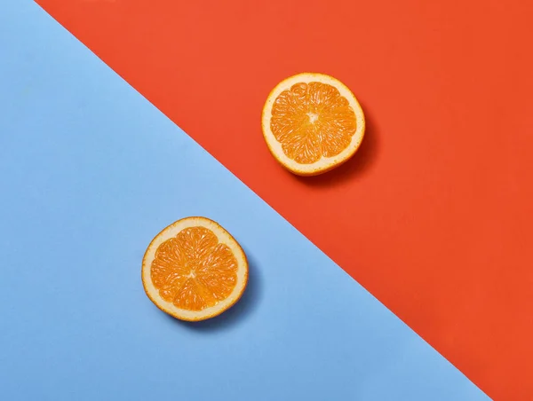 Dwie Połówki Pomarańczy Kombinacji Niebieskiego Czerwonego Tła — Zdjęcie stockowe