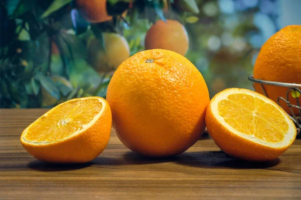 Egész Narancs Szeletek Asztalon Egy Gyümölcsfa Hátterében — Stock Fotó
