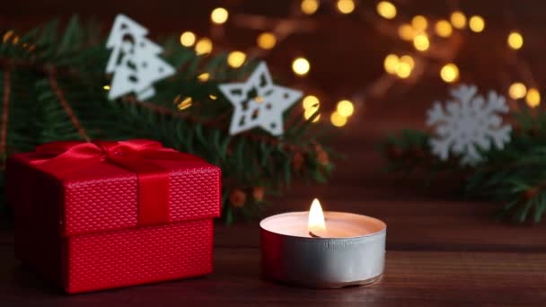 Fondo de Navidad con velas brillantes, caja de regalo, decoraciones navideñas, luces, ramas de árboles de Navidad y bokeh. Primer plano, enfoque selectivo — Vídeo de stock