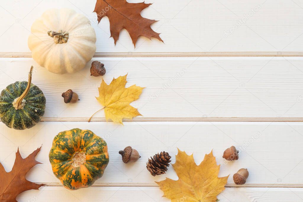 Autumn rustic composition with pumpkins, acorns and leaves on the wooden table with copy space. Thanksgiving concept
