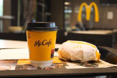Nuremberg, Almanya - 16 Temmuz 2021: McDonald 's' dan sarı fincan kahve ve hamburger. McDonald 's restoranında akşam yemeği..