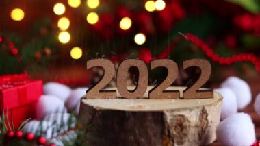 2022 numaralı odunların üzerine kar yağıyor. Noel süslemeleri, ışıklar, Noel ağacı dalları ve bokeh ile yeni yıl şenliği arka planı. Yakın çekim, seçici odaklanma