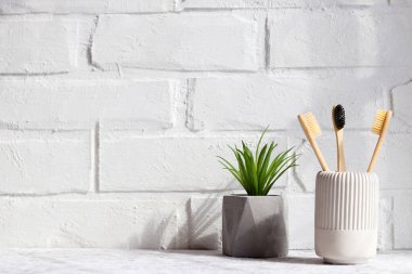 Bambu diş fırçaları ve sulu bitkiler. Çevre dostu banyo aksesuarları. Ağız temizliği ve sıfır atık konsepti. Minimalizm