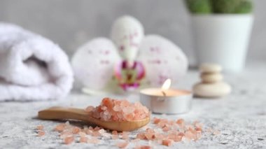 Pembe Himalaya tuzu, mum, orkide çiçeği ve havluyla ahşap bir kaşığa yakın plan. Güzellik ve kaplıca konsepti. Seçici odak