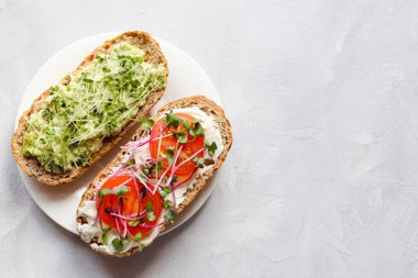 Avokado, domates ve mikroyeşillikli iki tost. Sağlıklı yiyecekler. Lezzetli ev yapımı aperatif ya da kahvaltı. Kopyalama alanı olan üst görünüm