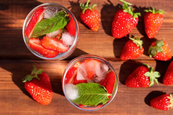Two glasses of fresh strawberry lemonade with ice and mint on the table. Summer refreshment drinks. Top view.