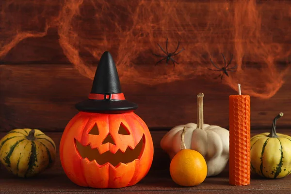 Cadılar Bayramı kartpostalı. Dekoratif balkabaklı Jack-o-latern ve iki örümcekli bir örümcek ağının arka planında mum. Seçici odak.