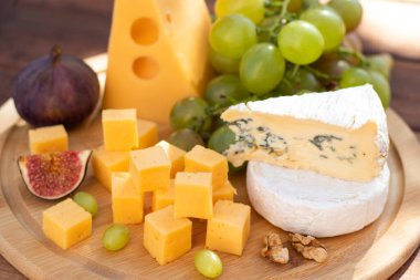 Farklı peynir çeşitleri olan peynir panosu. Brie, camembert, emmental, üzümlü ve incirli gouda. Seçici odak.