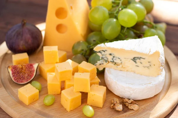 Farklı peynir çeşitleri olan peynir panosu. Brie, camembert, emmental, üzümlü ve incirli gouda. Seçici odak.