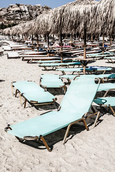 Liegestühle unter Palmen und Sonnenschirme am Strand — Stockfoto