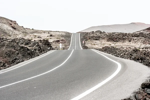 Strada vuota che attraversa una montagna arida, Lanzarote, Isole Canarie, Spagna — Foto Stock