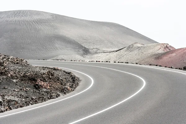 Leere Straße durch einen trockenen Berg, Lanzarote, Kanarische Inseln, Spanien — Stockfoto