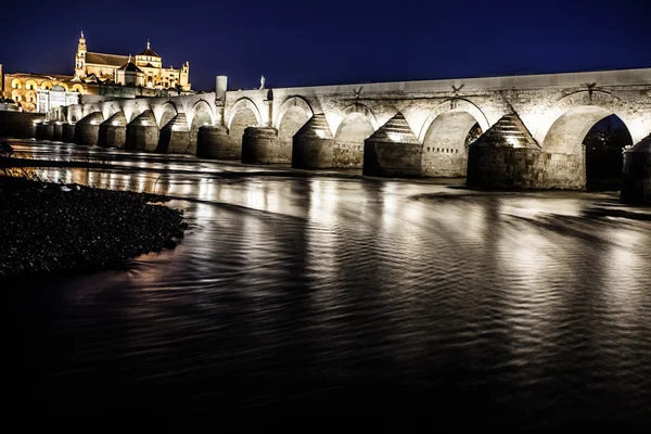 Římský most přes řeku guadalquivir a Velká mešita (katedrála mezquita) za soumraku v městě cordoba, Andalusie, Španělsko. — Stock fotografie