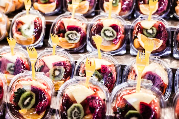 Fruitsalade gerangschikt in plastic bekers op een marktkraam focus op midden voorste cup. — Stockfoto