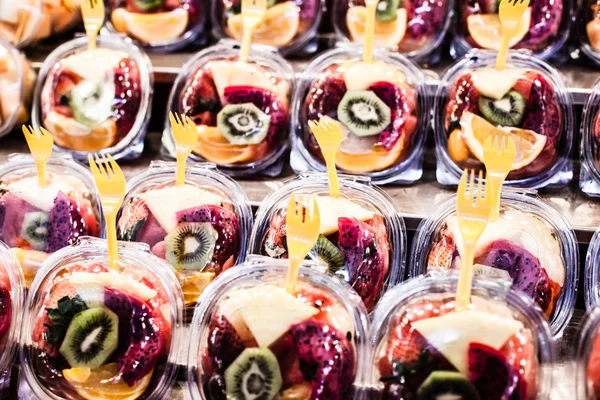 Fruit Salad arranged in plastic cups on a market stall focus on middle front cup. — Stock Photo, Image