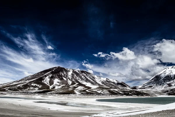 Aavikko ja vuori sinisen taivaan yllä ja valkoiset pilvet Altiplanossa, Boliviassa — kuvapankkivalokuva