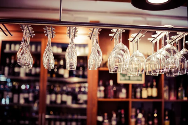 Empty glasses for wine above a bar rack — Stock Photo, Image